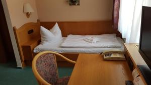 Kleines Zimmer mit einem Bett und einem Schreibtisch mit einem Computer. in der Unterkunft Hotel Sachsenhof in Riesa
