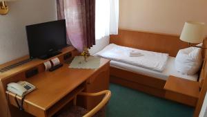 a room with a desk and a bed with a television at Hotel Sachsenhof in Riesa