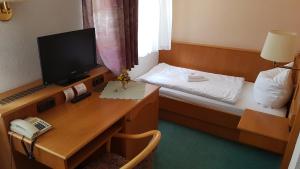 Habitación con escritorio y cama con TV. en Hotel Sachsenhof en Riesa