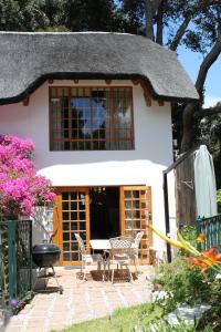 a house with a table and chairs in front of it at Plotsklaps Self Catering Cottage in Tokai