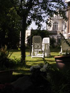 dos sillas blancas sentadas en el césped en un patio en Thermen Hotel Pension Villa Holstein, en Bad Salzuflen