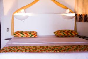 a bed with two pillows on it in a room at African Queen Lodge in Assinie
