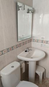 a bathroom with a sink and a toilet and a mirror at Viviendas Moreno Mar Menor in Santiago de la Ribera +20 photos