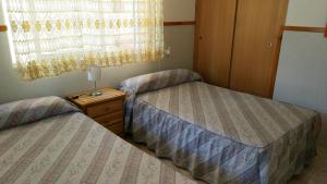 two beds in a small room with a night stand at Viviendas Moreno Mar Menor in Santiago de la Ribera