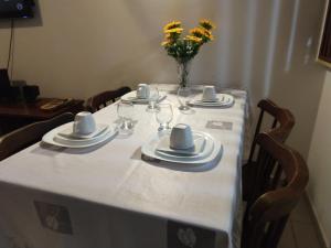 einen Tisch mit Tellern und Gläsern und eine Vase mit Blumen in der Unterkunft Flat Winterwille Gravatá in Gravatá