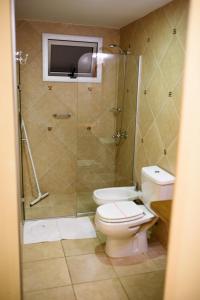 a bathroom with a toilet and a glass shower at AVEMAR Apart Hotel in Posadas