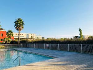 a swimming pool with a fence and a palm tree at Appartement 1 ROYAL VILLEROY in Sète