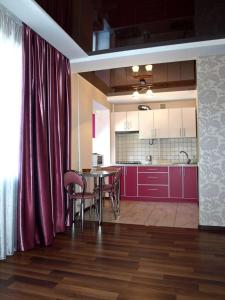 uma cozinha com armários vermelhos, uma mesa e cadeiras em Апартаменты с балконом em Kharkov