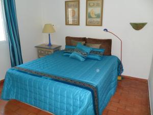 ein Schlafzimmer mit einem blauen Bett mit blauen Kissen in der Unterkunft Casa na praia e golfe in Vale do Lobo