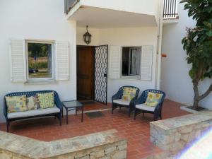 un patio con 3 sillas, una mesa y ventanas en Casa na praia e golfe, en Vale do Lobo