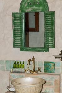 a bathroom with a sink and a green mirror at Limeni Inn Boutique Hotel Adults only 12plus in Limeni