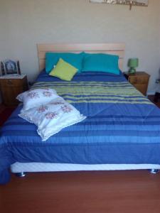 Una cama azul con dos almohadas encima. en Departamento Viña del mar, en Viña del Mar