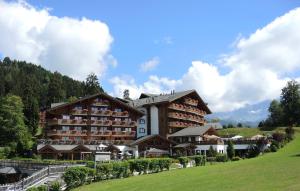 un gran hotel en una colina con un campo verde en Résidence RoyAlp - Appartement 22A, en Villars-sur-Ollon