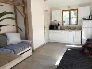 una cocina con armarios blancos y un sofá en una habitación en Chalet proche Orleans centre en Saint-Jean-le-Blanc