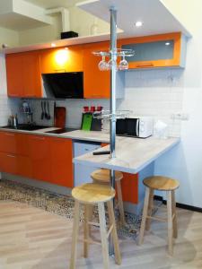 クラスノゴルスクにあるApartment on Geologov street 4/3のキッチン(オレンジ色のキャビネット付)、カウンター(スツール付)