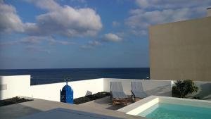twee stoelen en een zwembad met de oceaan op de achtergrond bij Casa Galana in Punta de Mujeres