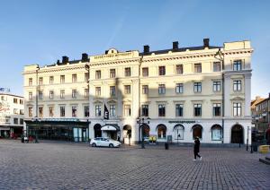 un gran edificio blanco con un coche delante en Elite Stora Hotellet Linköping, en Linköping