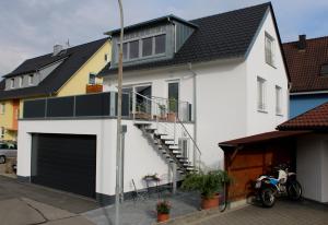 uma casa branca com uma porta preta e uma varanda em FeWo Bayha "Lerchenhaus" em Langenargen