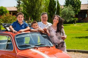 une femme et deux enfants debout à côté d'une voiture dans l'établissement Agriturismo Poggio Di Maremma, à Pescia Romana