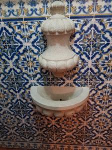 einen Steinbrunnen an einer Wand mit blauen und weißen Fliesen in der Unterkunft Casa da Piedade, Vouzela in Vouzela