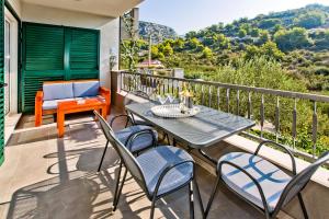 a patio with a table and chairs on a balcony at Luxurious Apartments Maslina with Beach in Milna