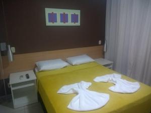 ein gelbes Bett mit zwei weißen Handtüchern drauf in der Unterkunft Aldeia das Águas Barrakana flats in Nossa Senhora das Dores + 19 Fotos