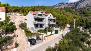 a house on a hill with a car parked in the street at Luxurious Apartments Maslina with Beach in Milna