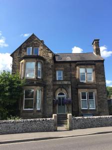 a stone house with a green door on a street at Avenue House in Bakewell