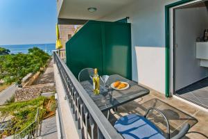 a table and chairs on a balcony with a view of the ocean at Luxurious Apartments Maslina with Beach in Milna