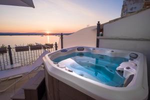 a jacuzzi tub on a balcony with the sunset at Palazzo Alfeo Aparthotel in Syracuse