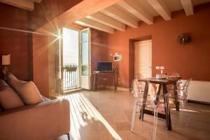 ein Wohnzimmer mit einem Tisch und einem TV in der Unterkunft Palazzo Alfeo Aparthotel in Syrakus