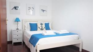 Un dormitorio con una cama blanca con almohadas azules. en Casa da Avó Irene, en Funchal