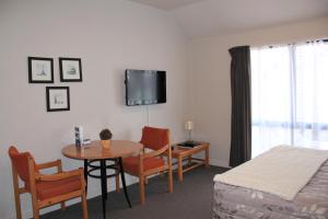 Habitación con mesa, cama, mesa y sillas. en Bush Inn Court Motel en Christchurch