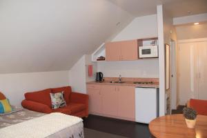 a living room with a red couch and a kitchen at Bush Inn Court Motel in Christchurch