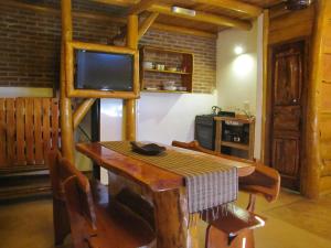 a dining room with a wooden table and a television at Loma Escondida Apart Cabañas & Spa in Villa Gesell