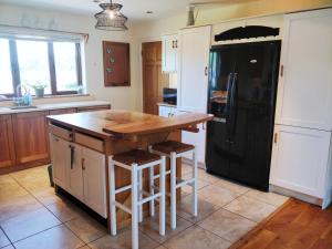 a kitchen with a wooden island and a black refrigerator at Luxury Skibbereen Town House in Skibbereen