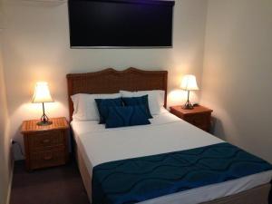 1 dormitorio con 1 cama con almohadas azules y 2 lámparas en Central Plaza Apartments, en Cairns