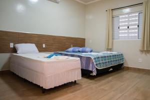 two beds in a room with a window at Hotel Pousada João 3.16 in Barretos