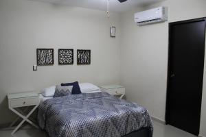 a bedroom with a bed and two tables and a air conditioner at Departamento zona dorada in Mazatlán