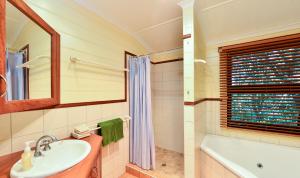 a bathroom with a shower, sink, and tub at Bushland Cottages and Lodge in Yungaburra