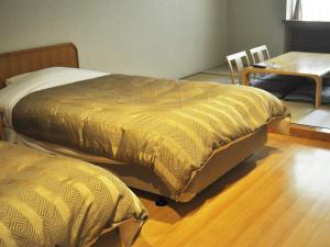 1 dormitorio con 2 camas, mesa, mesa y silla en Megahira Onsen Quelle Yoshiwa en Hatsukaichi