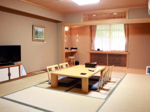 sala de estar con mesa, sillas y TV en Megahira Onsen Quelle Yoshiwa en Hatsukaichi