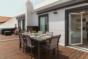 a black dining table and chairs on a deck at The Wave House in Baleal