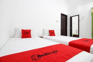ジョグジャカルタにあるRedDoorz near Adisucipto Airport 3の赤い枕付きのベッド2台が備わる客室です。