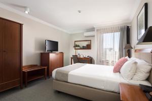a hotel room with a bed and a television at Ramada by Wyndham Brisbane Windsor in Brisbane