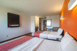 a hotel room with two beds and a flat screen tv at Motel 6 Omaha - IAT West in Omaha