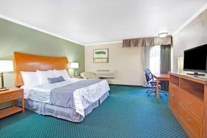 a hotel room with a bed and a flat screen tv at Days Inn by Wyndham San Jose Convention Center in San Jose