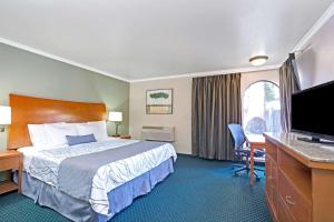 a hotel room with a bed and a flat screen tv at Days Inn by Wyndham San Jose Convention Center in San Jose