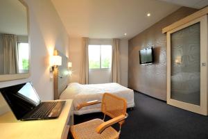 une chambre d'hôtel avec un lit et un ordinateur portable sur un bureau dans l'établissement inspiration by balladins Villefranche-de-Rouergue, à Villefranche-de-Rouergue