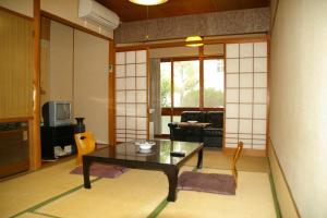 a living room with a table and a tv at Toramaru Ryokan in Kotohira